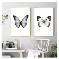 Two black and white butterfly prints on a wall
